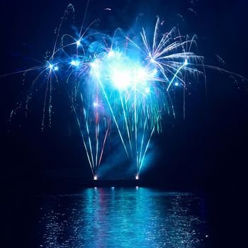 Blue colorful fireworks on the black sky background. Holiday celebration.