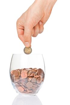 Hand putting 2 euro coin  into glass with euro cents isolated on white