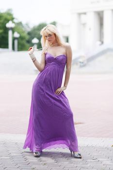 Standing blond girl in dress in summer day