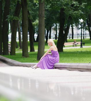 Girl blond sitting on steps in fashion dress