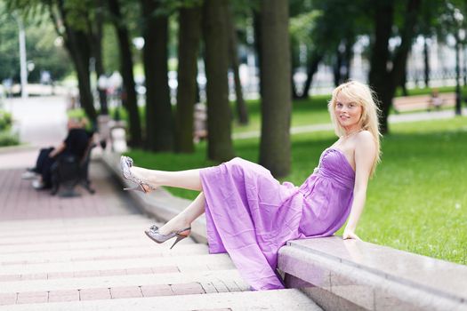 Blond Girl sitting on stairs in fashion dress