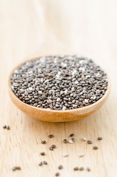 Chia seeds in wooden spoon on wooden background.