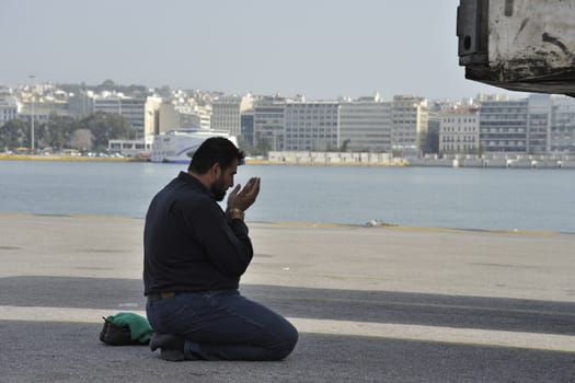 GREECE, Piraeus: A migrant prays after arriving from the islands at the port of Piraeus, on March 1, 2016, in Greece. Border restrictions further north in the Balkans have left thousands of refugees and migrants stranded in Greece.