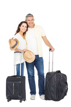 Happy couple embracing with straw hat and suitcase on white background