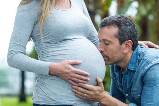 Man kissing pregnant womans stomach outdoors