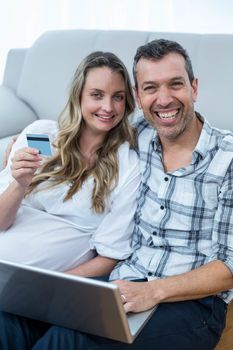 Expecting couple sitting on floor and using laptop