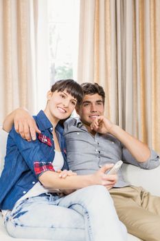 Romantic couple at home relaxing on the sofa watching television