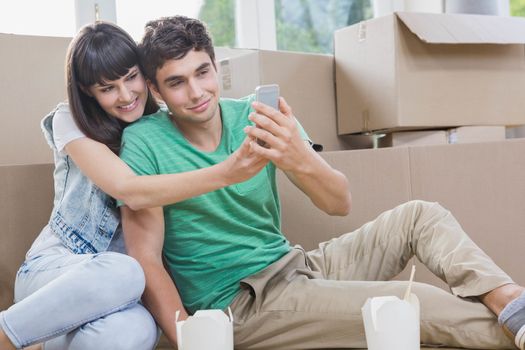 Young couple using mobile phone in their new house