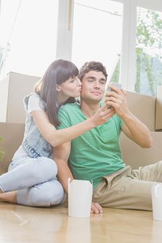 Young couple using mobile phone in their new house