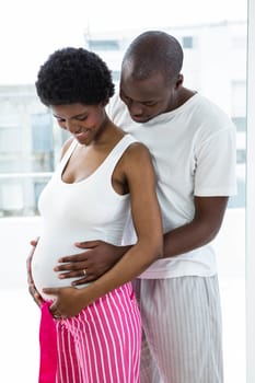 Pregnant couple embracing each other at home