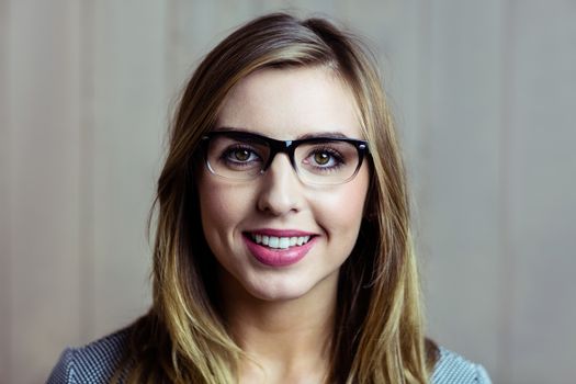 Pretty blonde woman smiling at camera on wooden background