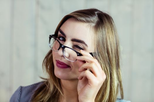 Pretty blonde woman blinking at the camera on wooden background