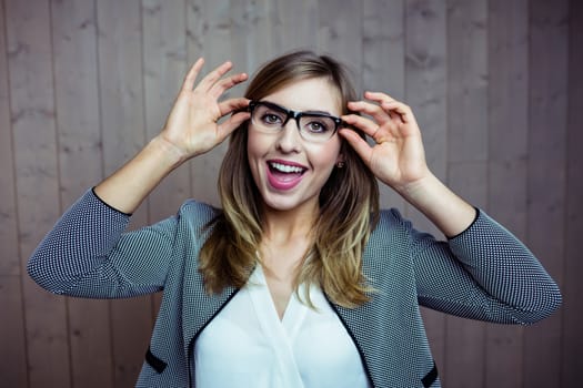 Pretty blonde woman smiling at camera on wooden background