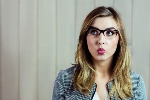 Pretty blonde woman making a funny face on wooden background