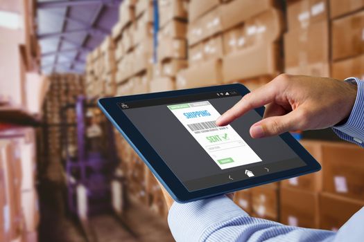 Man using tablet pc  against forklift in large warehouse