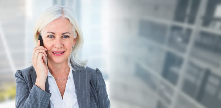 Portrait of businesswoman talking on mobile phone against modern room overlooking city