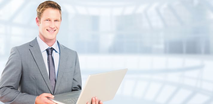 Happy businessman with laptop against modern room overlooking city