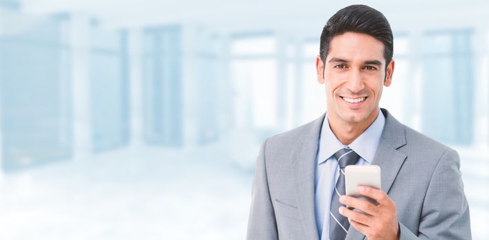 Businessman using mobile phone with colleagues behind against modern room overlooking city