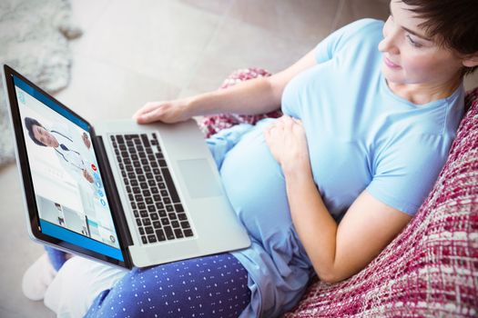 Pregnant woman using laptop at home against happy doctor sitting at his desk