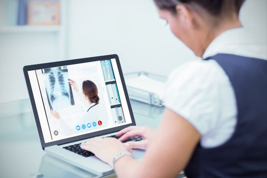 Female doctor studying Xray against business worker using laptop at desk