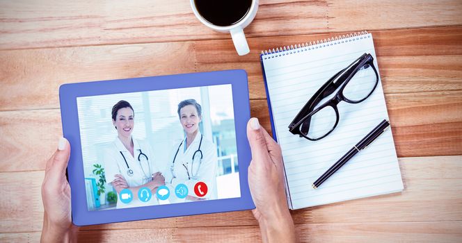 View of video chat app against overhead of feminine hands using tablet