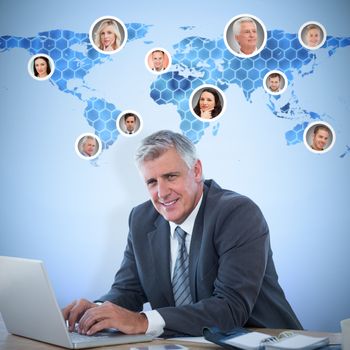 Smiling businessman working with his laptop against background with hexagons and world map