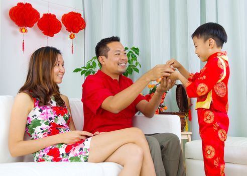 Asian boy presenting tea to his father during chinese new year