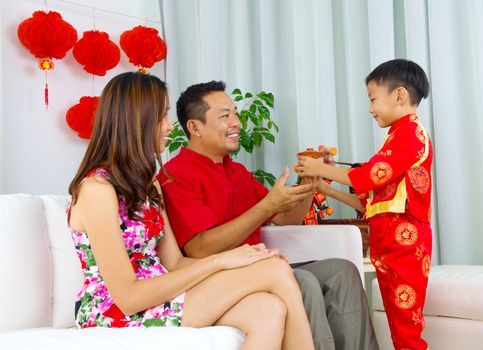 Asian boy presenting tea to his father during chinese new year