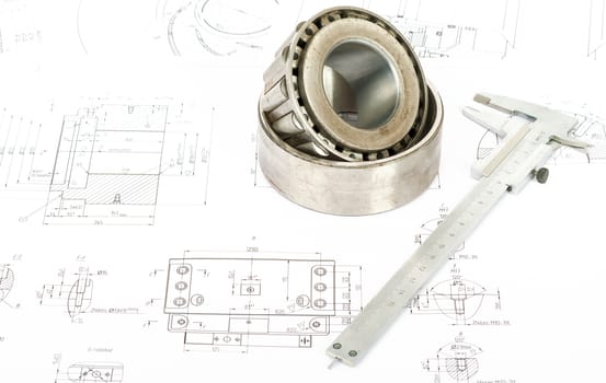 Roller bearing on blue prints with tool, closeup