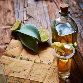 Tequila shot with lime and sea salt on wooden table, selective focus