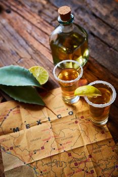 Tequila shot with lime and sea salt on wooden table, selective focus