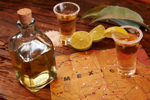 Tequila shot with lime and sea salt on wooden table, selective focus