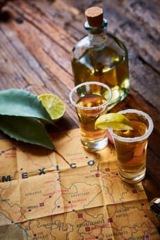 Tequila shot with lime and sea salt on wooden table, selective focus