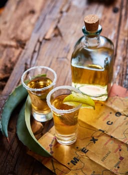 Tequila shot with lime and sea salt on wooden table, selective focus