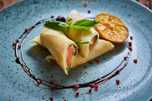 Crepes with smoked salmon on a blue plate for holiday