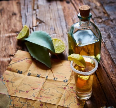Tequila shot with lime and sea salt on wooden table, selective focus