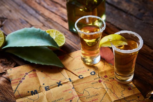 Tequila shot with lime and sea salt on wooden table, selective focus