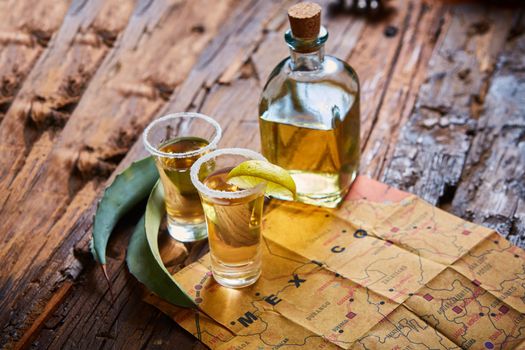 Tequila shot with lime and sea salt on wooden table, selective focus