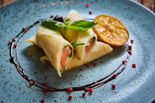 Crepes with smoked salmon on a blue plate for holiday