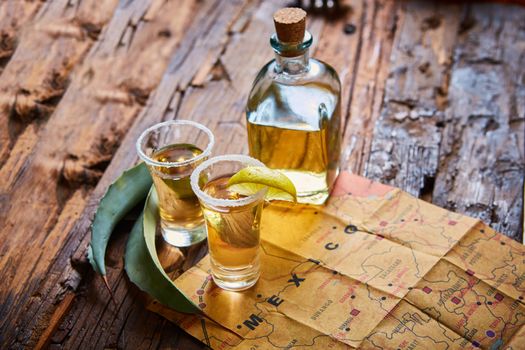 Tequila shot with lime and sea salt on wooden table, selective focus