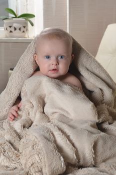 happy baby with a towel after the shower in bed at home