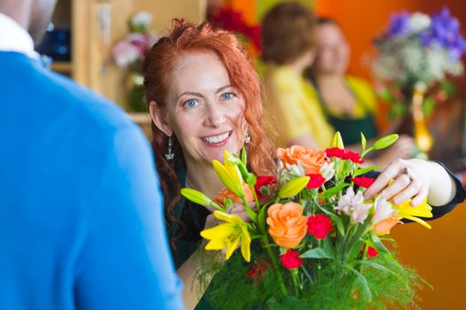 Female owner in a busy flower shop helping customer with bouquet