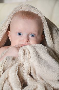 happy baby with a towel after the shower in bed at home