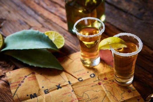 Tequila shot with lime and sea salt on wooden table, selective focus