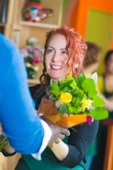 Woman selling bouquet in a busy flower shop