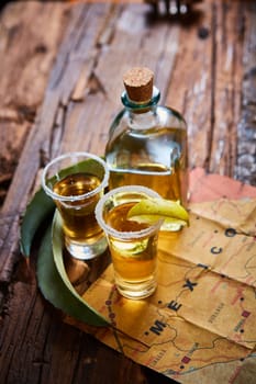 Tequila shot with lime and sea salt on wooden table, selective focus