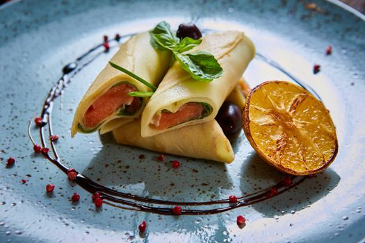 Crepes with smoked salmon on a blue plate for holiday