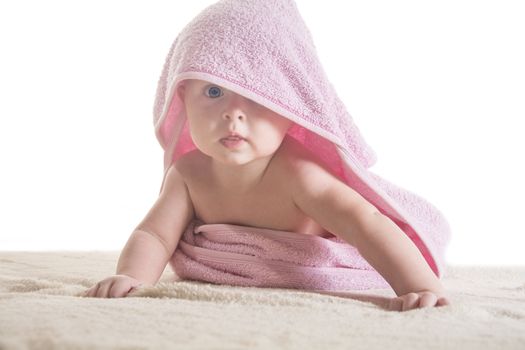 Sweet small baby covered with a rose towel with big eyes