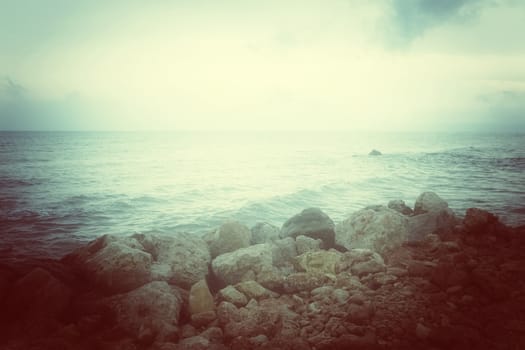 Sea and rocky coast in misty glow. Retro style photo.