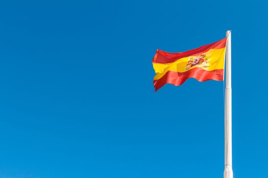 Spanish flag waving in the blue sky. Flag of Spain.